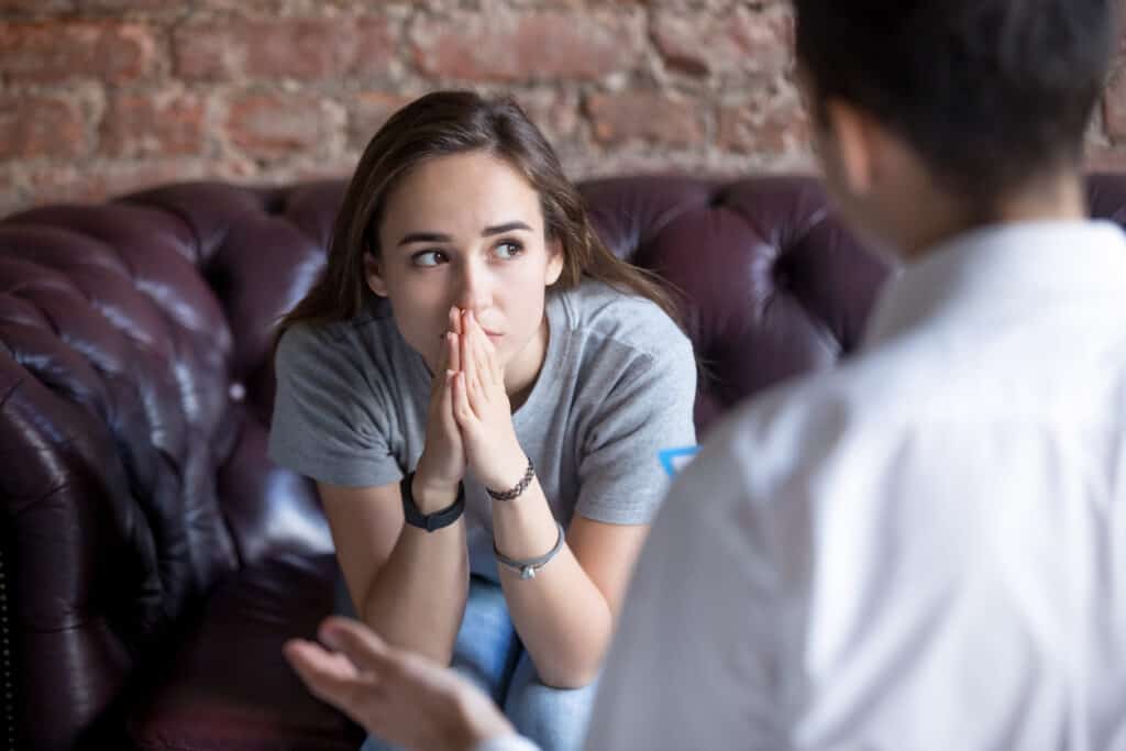 Woman sitting on a couch in front of a clinical director during addiction treatment