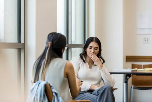 During partial hospitalization programs, woman puts fingers to lips and closes eyes while thinking