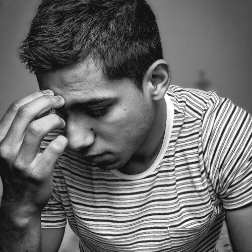 A vertical shot of an upset young male in grayscale